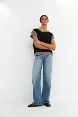 Top de tejido de punto en color negro, con cuello redondo, mangas cortas y detalles de rayas horizontales en blanco y negro en el cuello, las mangas y el ruedo.