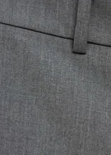 Pantalon de vestir gris de corte acampanado, con tiro medio, trabillas para cinturon, cierre oculto y bolsillos de ribete en la parte posterior.