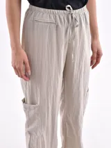Pantalón marrón de corte ancho, con cintura elástica ajustable con cordón, bolsillos laterales y bolsillos tipo cargo en los muslos.