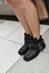 Botas cortas negras de cuero vacuno, con taco de 4 cm y plataforma delantera de 2 cm. Presentan una pieza superior desmontable con hebilla.
