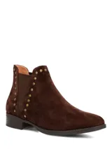 Botines de gamuza color marrón oscuro con diseño tipo chelsea, detalle de tachas metálicas a lo largo del elástico lateral y suela de goma con tacón bajo.