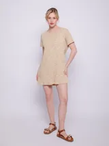 Vestido corto color beige con textura acanalada y cuello redondo. Es de manga corta y corte recto.