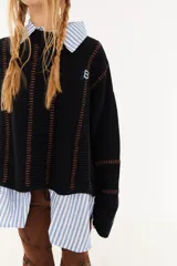 Sweater de punto color beige, con diseño de textura acanalada en mangas y espalda, cuello polo en color bordó y parche decorativo en la parte superior de la espalda.