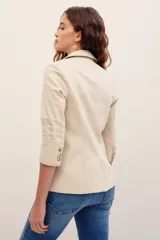 Saco sastrero de algodón color beige, de corte entallado con solapas clásicas, cierre de un botón frontal y bolsillos de ojal.