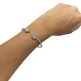 Pulsera rígida tipo esclava hecha en acero con zirconia, con forma de lágrima en un extremo y forma rectangular en el otro.