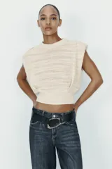Jersey de punto sin mangas con cuello redondo, diseño de hombreras marcadas y textura acanalada horizontal.