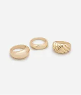 Set de tres anillos dorados de metal con efecto bold, uno texturizado y dos lisos con diferentes formas.