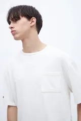 Remera color crudo de algodón con calce oversize, manga corta, cuello redondo y estampa en la espalda con texto en color negro.