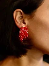 Caravanas de diseño circular compuestas por pequeñas cuentas de vidrio en color rojo intenso, con cierre de clip.