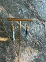 Aros colgantes elaborados con piedras naturales de jaspe imperial en tonos azules y marrones, envueltos en alambre dorado en la parte superior y con gancho metálico.