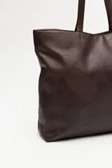 Cartera tote negra de símil cuero con diseño texturizado de parches y asas largas.