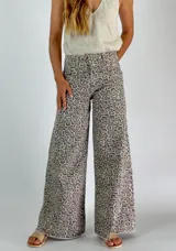 Pantalón jean de corte ancho con estampado animal print en tonos beige y gris.