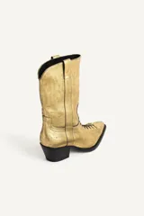 Botín de piel estilo cowboy con acabado metalizado dorado, cordones en el empeine, tacón medio ancho asimétrico y puntera perfilada.