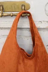 Cartera tipo hobo de gamuza negra, con diseño minimalista y asa integrada.