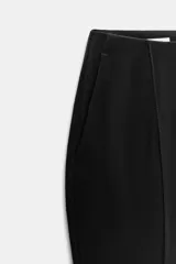 Pantalón de tiro bajo negro, corte flare con bajo evasé, bolsillos delanteros y cierre frontal con cremallera y botones.