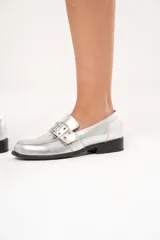 Mocasines plateados de cuero con hebilla y ojalillos.