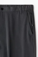 Pantalón de vestir gris oscuro, corte slim fit, con bolsillos laterales y traseros. Cierre frontal con botón y cremallera.