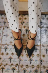 Zapato de tacón alto tipo destalonado, con acabado en punta y escote redondo. Presenta una tira fina ajustable con hebilla metálica en el tobillo y tacón fino.