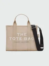 Bolso tote mediano de lona color celeste con estampado frontal del logo "The Tote Bag" en blanco y el nombre de la marca "Marc Jacobs" en la parte inferior. Tiene doble asa de mano y correa de hombro ajustable y extraíble.