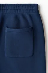 Pantalón deportivo azul marino confeccionado en felpa de mezcla de algodón, con cintura elástica ajustable, bolsillos laterales y bajos con elástico fruncido.