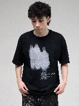 Remera negra de corte oversize con cuello redondo y estampado frontal en color blanco con efecto de pintura en aerosol y texto.