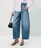 Pantalón de jean estilo barrel con cintura alta, cierre frontal con botón y cremallera, y recortes laterales que definen su silueta amplia y moderna.