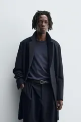 Abrigo de corte regular fit confeccionado en tejido compacto con mezcla de lana. Presenta cuello con solapas de muesca, cierre frontal de botonadura, bolsillos de vivo en la cadera y abertura central en la espalda.