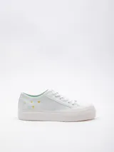 Zapatillas bajas de lona color celeste con plataforma blanca texturada y detalle de flores bordadas en el lateral.