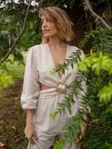 Mono largo color avena, con escote en V, mangas 3/4 abullonadas y detalle de abertura en la cintura con hebilla cuadrada de rafia.