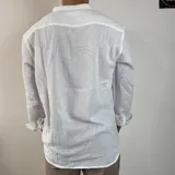 Camisa blanca de manga larga con cuello mao y abertura frontal con botones de madera. Tejido ligero con textura de lino.