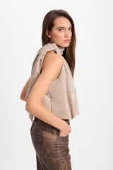 Blusa sin mangas de corte holgado con cuello alto tipo halter y pliegues frontales. Confeccionada en tela con textura sutil.