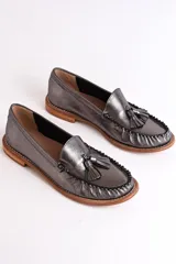 Mocasines negros de cuero con borlas y costuras decorativas.