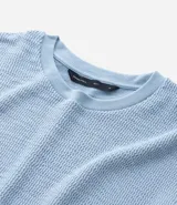 Remera celeste de algodón texturizado, corte boxy, cuello redondo y manga corta.