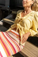 Camisa amarilla de broderie con escote en V, mangas globo y lazos ajustables en el frente.