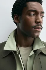 Sobrecamisa de corte boxy fit confeccionada en tejido compacto color beige, con cuello solapa, cierre frontal de botones y bolsillos laterales en costura.