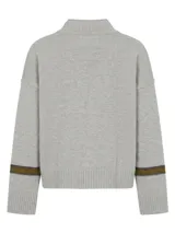 Polera de lambswool color marrón, con cuello media polera, diseño de rayas horizontales en contraste en la parte superior delantera y en las mangas, y detalle de pin con logo en el puño.