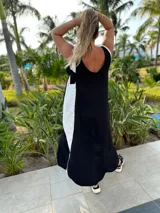 Vestido largo negro con panel lateral blanco, escote en V en la espalda y corte holgado.