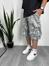 Bermuda de corte holgado con estampado de camuflaje en tonos grises y blancos, con bolsillos laterales tipo cargo.