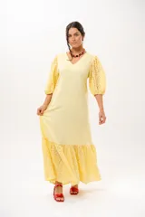 Vestido largo amarillo mantequilla con escote en V, mangas abullonadas y volados en el bajo con detalles de broderie.