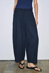 Pantalón de tiro medio confeccionado en mezcla de lyocell, con diseño de pierna ancha y tejido en espiga. Cuenta con cintura elástica ajustable con cordones y bolsillos laterales.