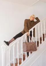 Bolso de mano tipo shopper marca Amadea, confeccionado en cuero con acabado desgastado. Presenta detalles de costuras decorativas verticales, correas con hebillas metálicas doradas y logo grabado al frente.