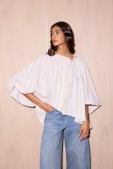 Camisa holgada de algodón con cuello alto y mangas anchas, confeccionada en Italia. Presenta un estampado de rayas verticales finas en tonos beige, blanco, amarillo, rojo y azul.