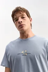 Remera celeste de manga corta y corte clásico, con estampa en la espalda de flores en tono amarillo claro y texto motivacional.