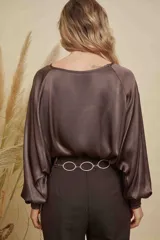 Blusa de satén color champagne con cuello a la base, mangas anchas y puños elásticos con detalle bordado.