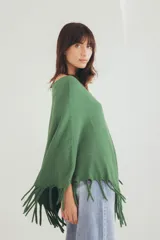 Poncho tejido de punto en color verde, con diseño holgado, cuello redondo y terminación con flecos en el ruedo.