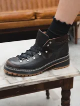 Borcego de cuero negro con cordones y suela track color caramelo.