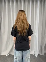 Remera negra de algodón con estampa frontal en serigrafía plastisol de diseño tipográfico estilizado en color blanco. Presenta cuello redondo reforzado, corte regular y grifa de la marca LuccaBossio en la manga.
