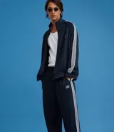 Pantalón deportivo de corte recto y holgado, color negro con rayas blancas laterales. Cuenta con cintura elástica con cordón ajustable, bolsillos laterales y detalle de costura vertical frontal.