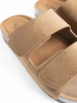 Sandalia de dos tiras con cierre de velcro, confeccionada en material símil cuero color gris. Cuenta con plantilla anatómica con base de corcho y suela de goma negra.
