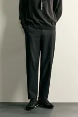 Pantalón regular fit de hombre color negro, confeccionado en tejido técnico ligero con cintura elástica, bolsillos frontales, bolsillos traseros de vivo y cierre frontal con cremallera y botón.